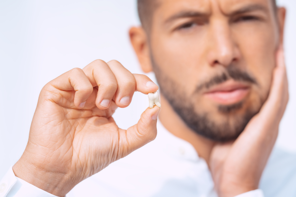 dental emergency man holding a fallen out tooth